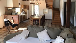 A cozy living room with a sofa, a dining table, and a kitchen in the background.