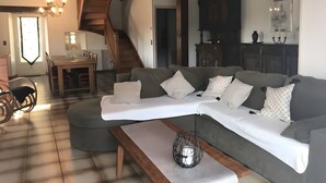 A living room with a sectional sofa, a wooden coffee table, a chandelier, and a staircase.