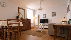 Un salon chaleureux avec une table à manger en bois, des chaises, un téléviseur et un canapé.