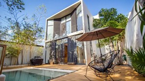 Uma casa moderna de dois andares com piscina, deck de madeira e área de estar externa.