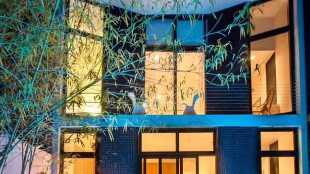 Uma casa moderna de dois andares com piscina, grandes janelas e área de estar coberta ao ar livre.