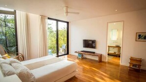 Quarto moderno com uma cama grande, televisão e porta de correr para uma varanda.