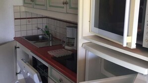 Une cuisine de taille réduite, avec des meubles blancs, un four à micro-ondes et un lave-vaisselle.