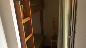 Une petite pièce avec un lit superposé, une chaise et un rideau.
