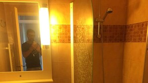 Une salle de bain avec une douche à parois de verre, un lavabo et un miroir.
