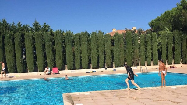 Une piscine dont le fond est recouvert de carrelage, sous un ciel d’un bleu limpide.
