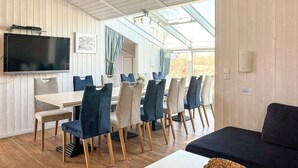 Una habitación acogedora con una mesa de comedor, sillas, un sofá y un televisor montado en la pared.