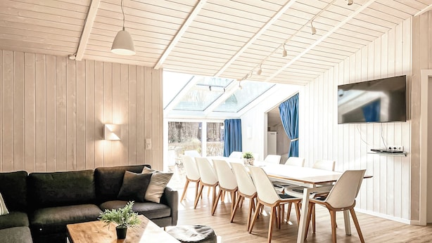 Ein modernes Wohnzimmer mit Sofa, Couchtisch und Essbereich mit Stühlen und Tisch.