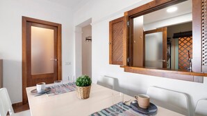Un comedor con una mesa, sillas, una planta en maceta y un espejo.