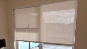 A bedroom with a large window, a bed, and a nightstand with a lamp. - Brand new condo in heart of Willoughby Town Centre Langley BC (Langley Township)