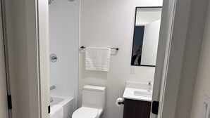 A modern bathroom with a toilet, bathtub, and sink. - Brand new condo in heart of Willoughby Town Centre Langley BC (Langley Township)