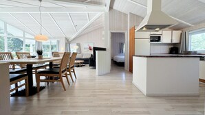 Cozinha ampla com ilha central, mesa de jantar de madeira e cadeiras.
