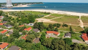 Vista aérea de uma área costeira com praia, edifícios residenciais e um hotel alto.
