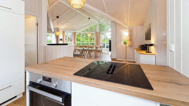 A modern kitchen with a large island, built-in oven, and pendant lighting. - Beach view vacation home 19 (Lübeck-Travemünde)