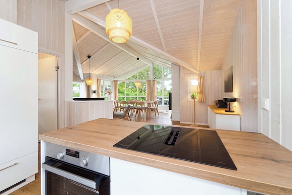 Una cocina moderna con una isla grande, horno empotrado e iluminación colgante.