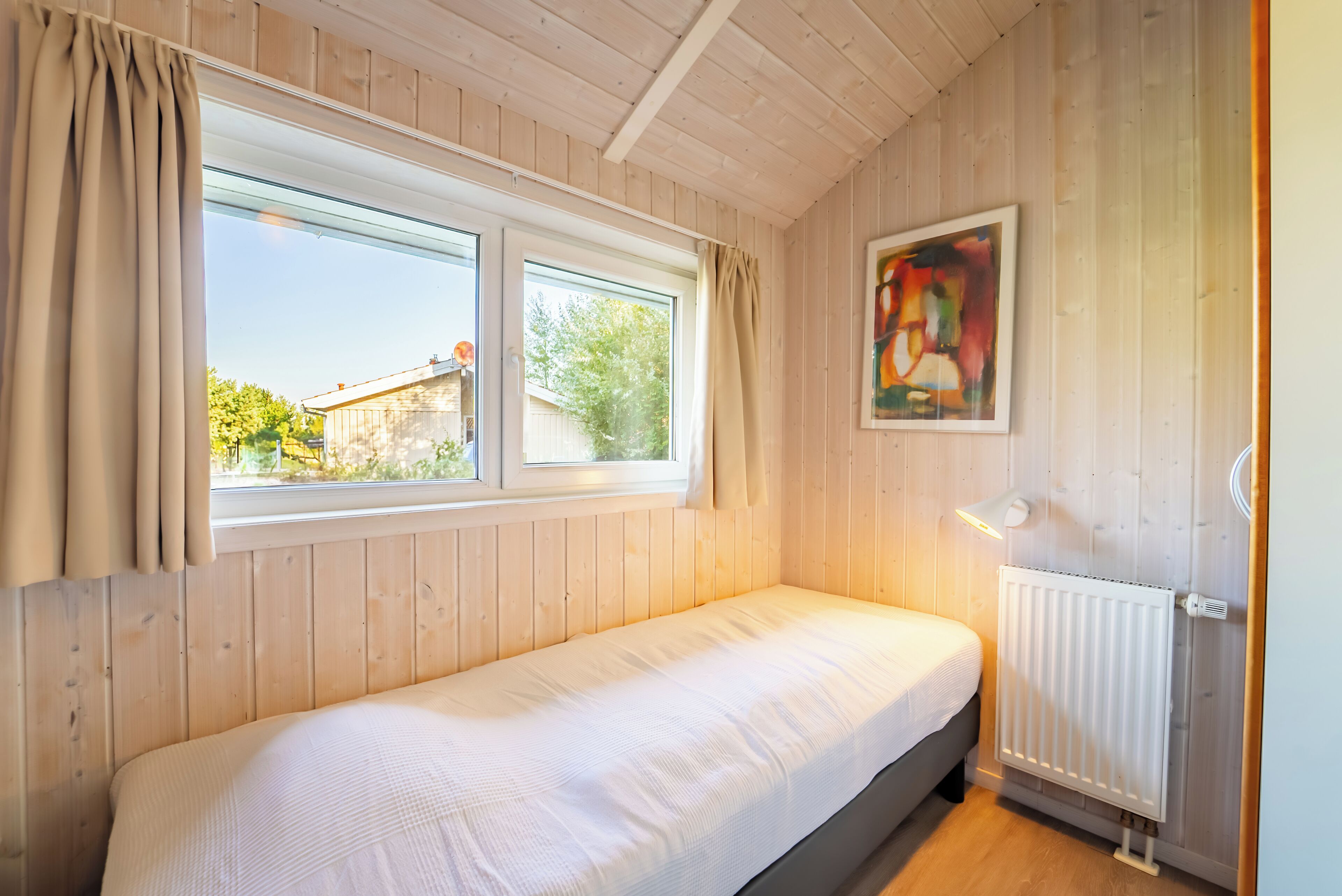 Un letto singolo in una stanza con pareti in legno e una finestra.