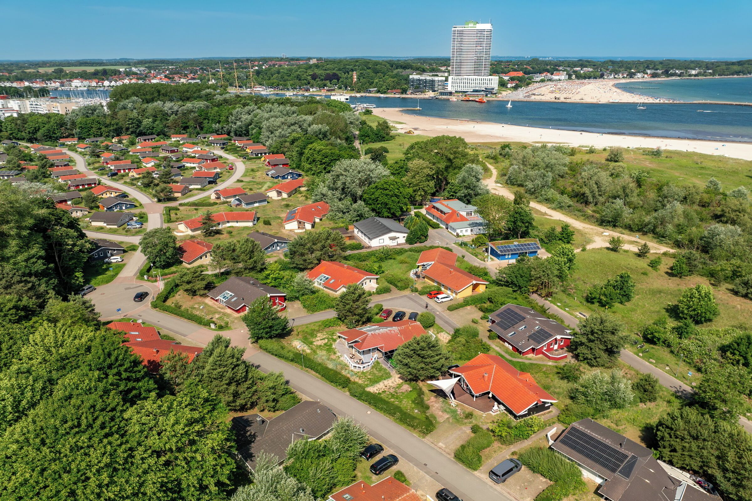 An aerial view of a residential area with houses, roads, and a beach.