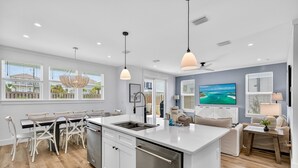 A modern kitchen with a central island, white cabinetry, and pendant lighting. - Oceans East: Private heated pool, Free golf cart, 1 min beach, Game & Bunk rooms (Miramar Beach)