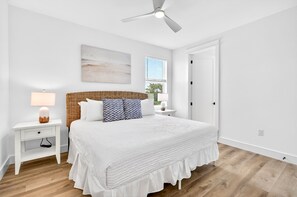A bedroom with a bed, a nightstand, a lamp, a ceiling fan, a window, and a door. - Oceans East: Private heated pool, Free golf cart, 1 min beach, Game & Bunk rooms (Miramar Beach)