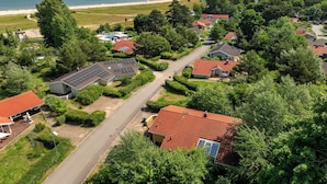Et boligområde med huse, en vej og en strand i baggrunden.