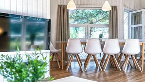 Un'area pranzo moderna con un tavolo in legno, sedie bianche e lampade a sospensione.