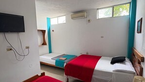 A room with two beds, a TV, an air conditioner, and a window. - El Descanso del Petrel (Puerto Ayora)