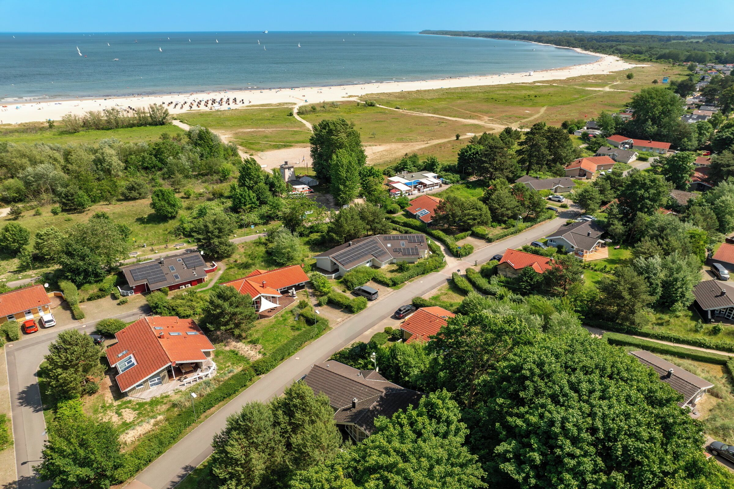 Eine Vogelperspektive eines Küstenwohngebiets mit Häusern, einem Strand und blauem Himmel.