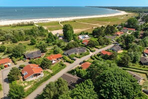 An aerial view of a coastal residential area with houses, a beach, and a clear sky. - Vacation Home with Beach View 16 (Lübeck-Travemünde)