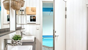 Un baño con dos lavamanos, un espejo y una puerta que da a una zona de piscina.