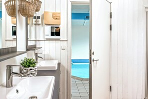 A bathroom with two sinks, a mirror, and a door leading to a pool area. - Beach view vacation home 16 (Lübeck-Travemünde)