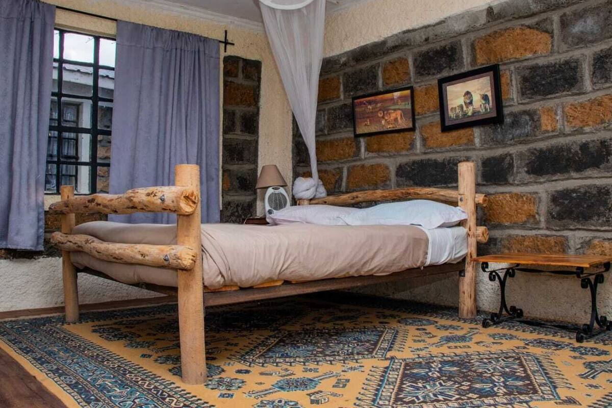 Una habitación rústica con una cama de madera, un tapete estampado y una pared de ladrillo.