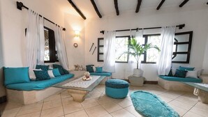 A cozy living room with teal sofas, a coffee table, and a potted plant.