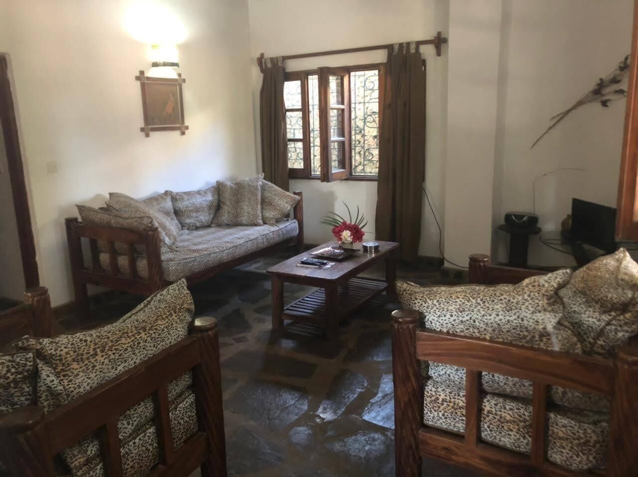 A cozy living room with a sofa, two armchairs, a coffee table, and a window with curtains.