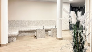 Un bagno moderno con una panca, due lavandini e una pianta decorativa.