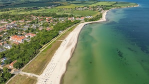 Vista aerea di una cittadina costiera con spiaggia, case e una limpida visuale sul mare.