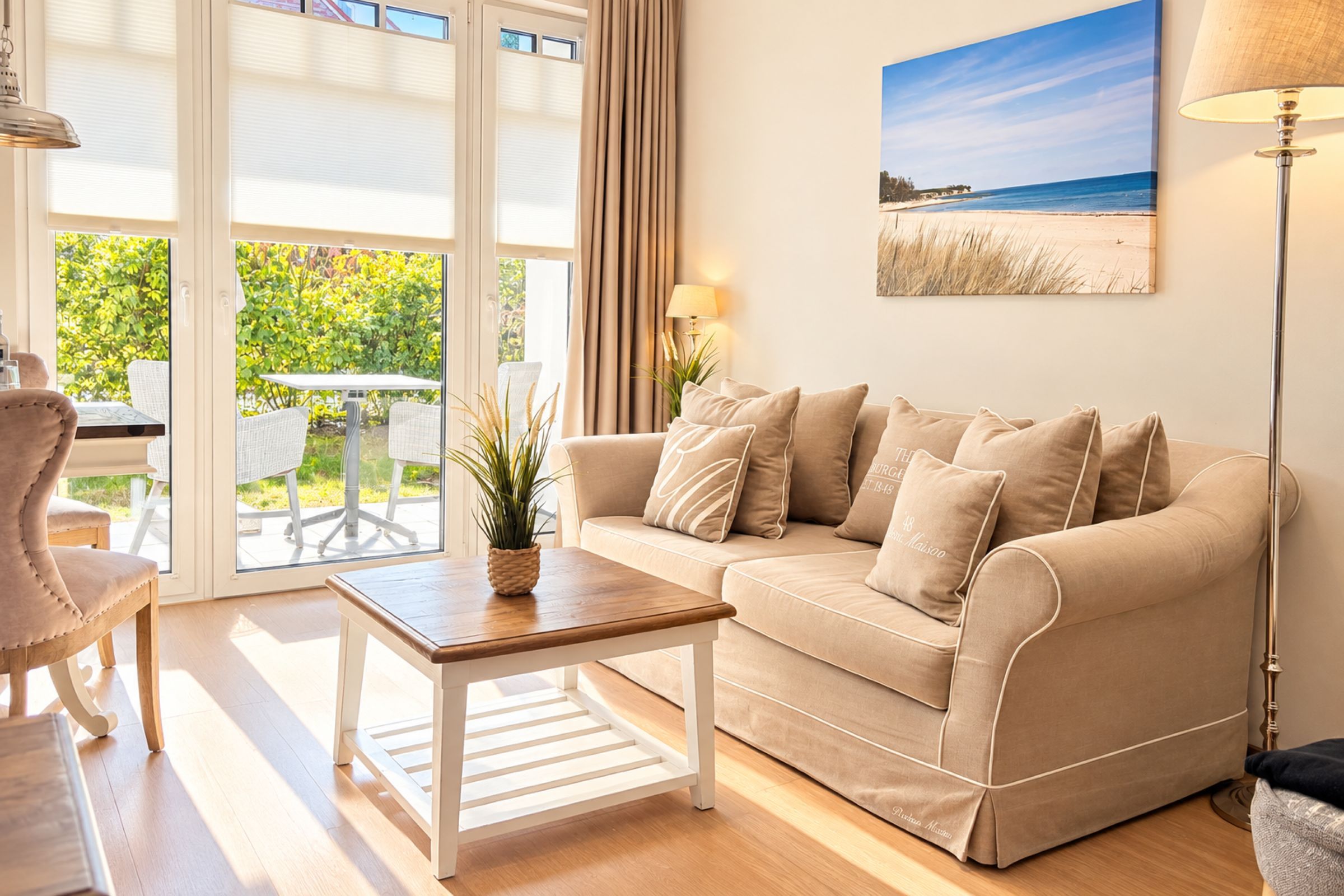 Ein Wohnzimmer mit einem beigen Sofa, einem Couchtisch, einer Lampe und einem Gemälde vom Strand.