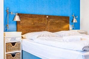 A bed with white linens, two bedside tables, and a wooden headboard.