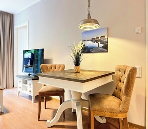 Ein Essbereich mit Tisch, Stühlen, einem Fernseher und einem Bild an der Wand.