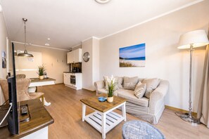 A modern living room with a sofa, coffee table, and a dining area with a table and chairs.