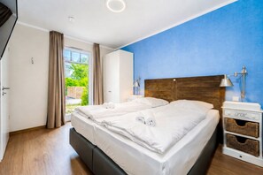 Een hotelkamer met een tweepersoonsbed, een nachtkastje met een lamp en uitzicht op groen.