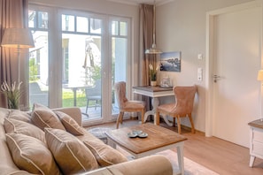 A living room with a sofa, two chairs, a coffee table, and a desk with a chair. - Baltischer Hof, Apartment 14 (Ostseebad Boltenhagen)