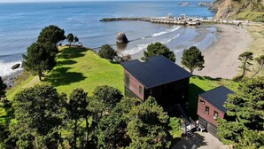 A coastal property with a beach, a pier, and a small building with a dark roof. - Most Spectacular Ocean Views - Studio (Port Orford)