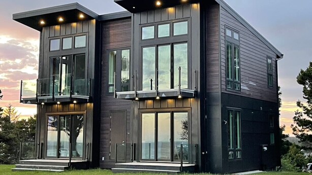 Een modern huis met twee verdiepingen, grote ramen en een balkon.