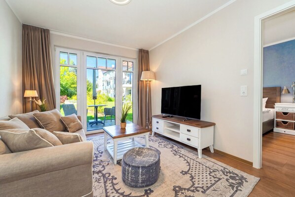 Ein Wohnzimmer mit Sofa, Fernseher und einem kleinen Tisch mit Pflanze.