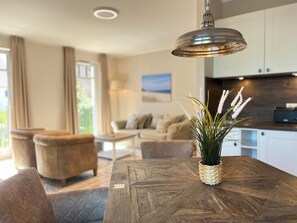 A modern living room with a wooden coffee table, a hanging pendant light, and a potted plant. - Baltischer Hof apartment 21 (Ostseebad Boltenhagen)