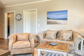 Ein Wohnzimmer mit einem beigen Sofa, einem passenden Sessel und einem Holztisch.