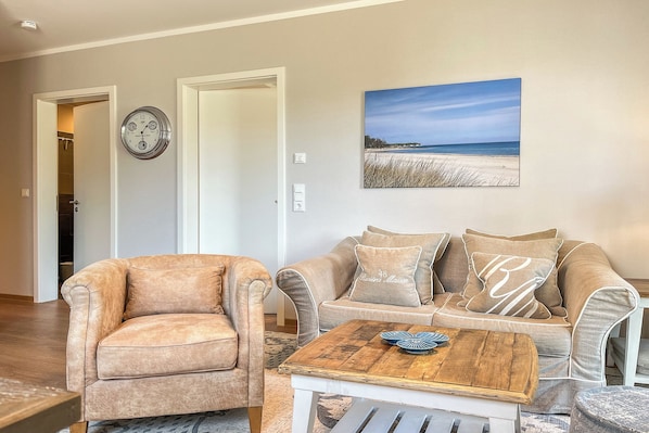 A living room with a beige sofa, a matching armchair, and a wooden coffee table. - Baltischer Hof apartment 04 (Ostseebad Boltenhagen)