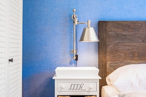 A white bedside table with a drawer containing the word 'SLEEP' and a wall-mounted lamp. - Baltischer Hof Apartment 04 (Ostseebad Boltenhagen)