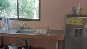 Una cocina equipada con lavaplatos, cafetera, hervidor y refrigerador.