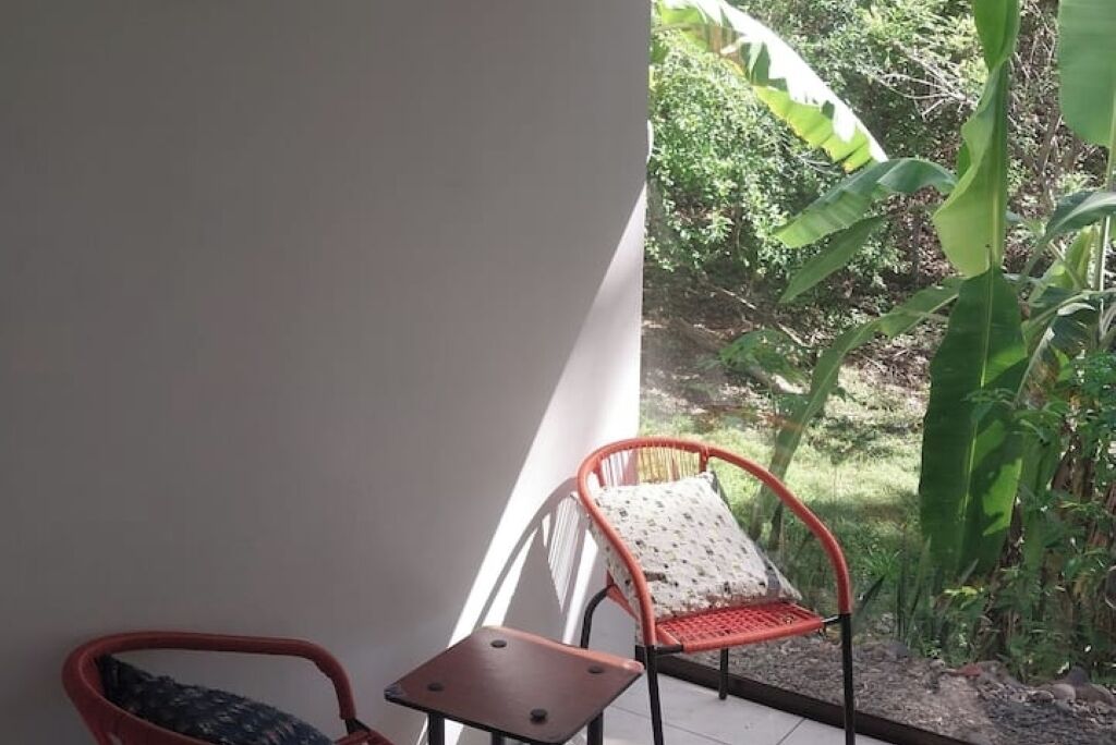 Ein Balkon mit zwei Stühlen, einer mit gemustertem Sitzkissen und der andere mit einem einfarbigen Sitzkissen.